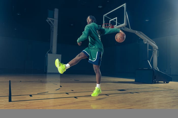 Tyrese Maxey models green New Balance apparel on a basketball court.